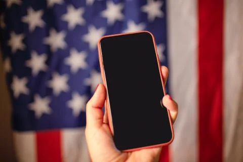 Womans hand holding smartphome with aempty black screen with a american flag on Stock Photos