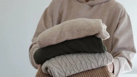 Woman's hand holding a stack of clothes. Clothes Donation, Renewable Concept Stock Footage 167242316