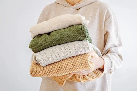 Woman's hand holding a stack of clothes. Clothes Donation, Renewable Concept Stock Photos