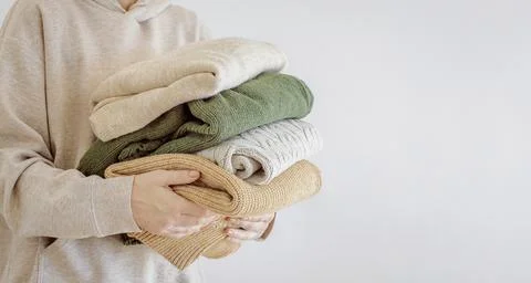Woman's hand holding a stack of clothes. Clothes Donation, Renewable Concept Stock Photos