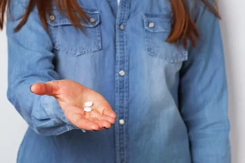 Woman's a hand holding two white pills. Stock Photos