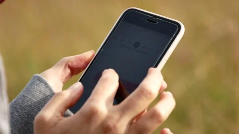 A woman's hand holds and using smartphone in nature. 4k 動画素材 116160525