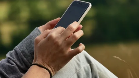 A woman's hand holds and using smartphone in nature. 4k 스톡 동영상 116161267
