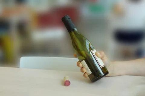 Woman's hand holds a bottle while pouring wine Stock Photos