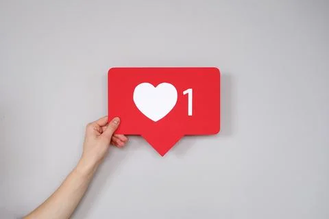 A woman's hand holds a Like button in the form of a heart Stock Photos
