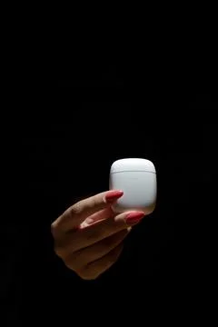 A woman's hand holds a case for wireless headphones the background is blurred Stock Photos