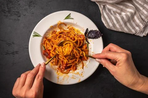 Woman's hand holds a fork with a paste with tomato and pesto Stock Photos