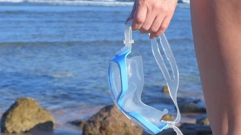 Woman's hand holds mask for diving, a background of blue sea water. Video stock 83166802