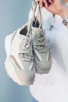 A woman's hand holds a pair of comfortable shoes in her hands. sneakers. woman Stock Photos