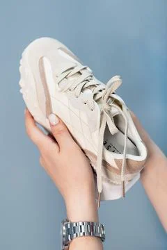 A woman's hand holds a pair of comfortable shoes in her hands. sneakers. woman Stock Photos