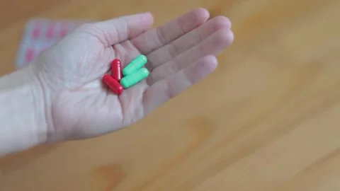 A woman's hand holds a pair of multi-colored capsules of pills, clenches a fist Stock Footage 262422646