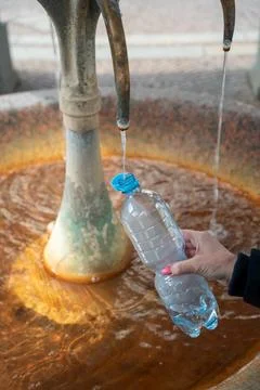 A woman's hand holds a plastic bottle and draws healing hot water from the .. Foto stock