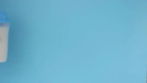 Woman's hand holds protein shake on blue background, front view Stock Footage 132174664