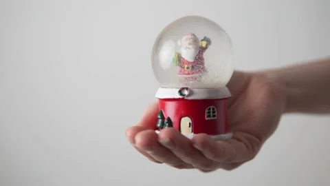 A woman's hand holds a snow globe with Santa Claus, snow is drunk Stock Footage 143689666