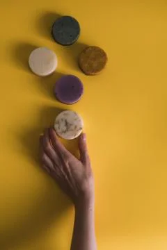 A woman's hand holds a solid bar of shampoo or soap. Stock Photos