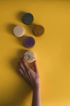 A woman's hand holds a solid bar of shampoo or soap. Stock Photos