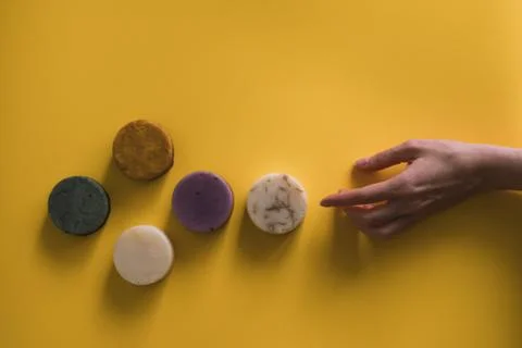 A woman's hand holds a solid bar of shampoo or soap. Stock Photos