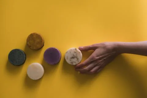 A woman's hand holds a solid bar of shampoo or soap. Stock Photos