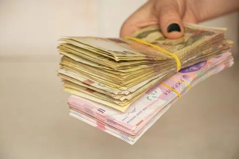 A woman's hand holds a stack of Ukrainian hryvnias, giving money, one hundred Stock Photos