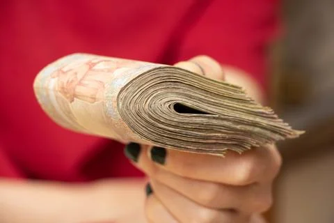 A woman's hand holds a stack of Ukrainian hryvnias, giving money, one hundred Stock Photos