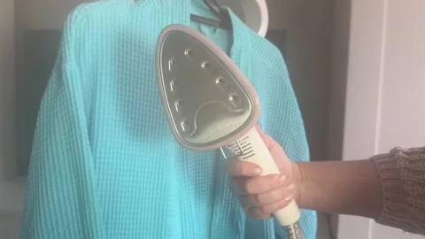 A woman's hand holds a steamer from which steam comes out, dry cleaning, clothes Stock Footage 255038540