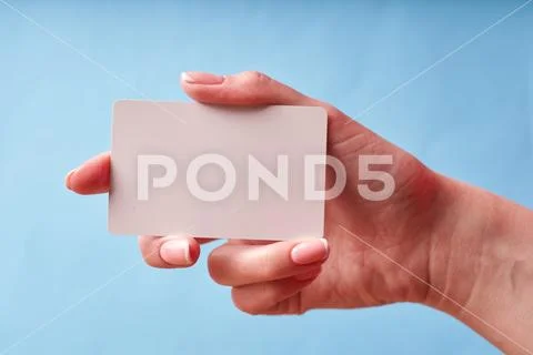 A woman's hand holds a white plastic card. Isolated card in hand Stock Photos