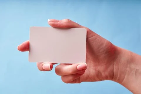 A woman's hand holds a white plastic card. Isolated card in hand Stock-Fotos