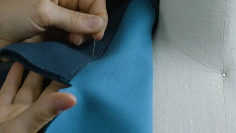 Woman's hand inserting needle into blue fabric Stock Footage 124279687