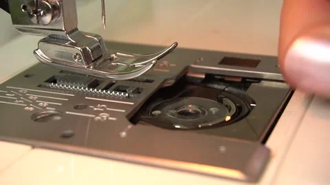 A woman's hand inserts the bobbin case under the hook plate. Stock-Footage 139062831