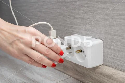Woman's hand inserts charging into the socket 写真素材