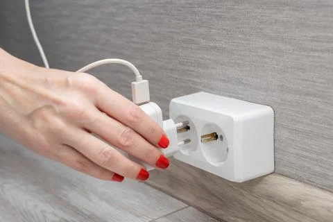 Woman's hand inserts charging into the socket Stock Photos