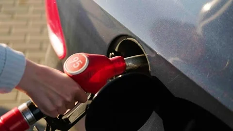 A woman's hand inserts a gas station gun into the tank of a blue car close-up Stock Footage 240561371