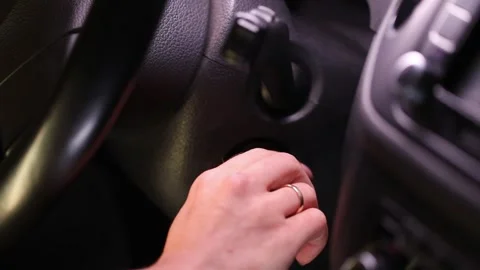A woman's hand inserts the key into the ignition lock and starts the car engine. Stock Footage 244111004