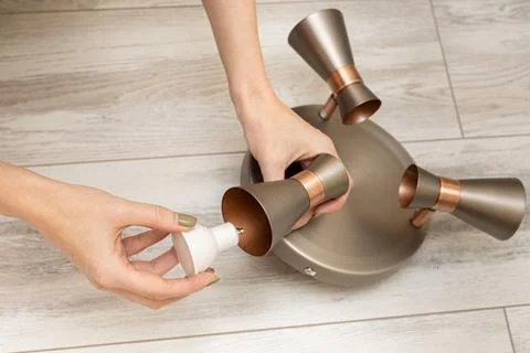 A woman's hand inserts a light bulb into a lamp socket Foto stock