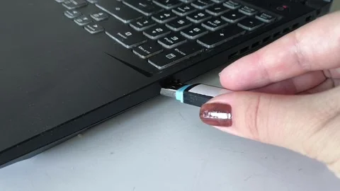 A womans hand inserts a USB flash drive into the laptop connector close-up. Data Stock Footage 320523722
