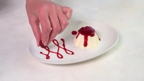 Woman's hand lays raspberry berries and mint leaf to panna cotta Stock Footage 149253354