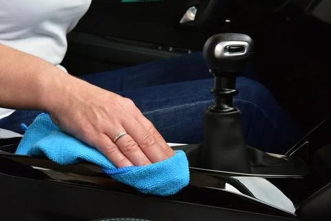Woman's hand with microfiber cloth cleaning car console Stock Photos