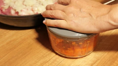 Woman's hand mincing carrots in a manual food chopper Video stock 342758632
