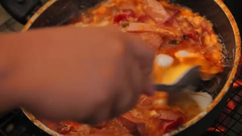 A woman's hand mixes scrambled eggs with vegetables and sausage in a frying pan Stock Footage 136744482