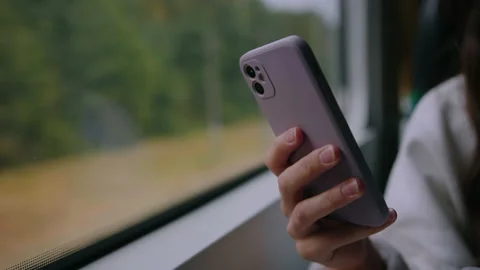 Woman's hand with a mobile phone on the background of a window on a train Видео 218439933