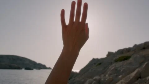 A woman's hand moves softly and lightly under the sun's rays by the sea Stock Footage 287311153