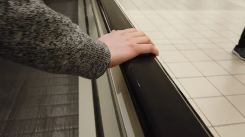 Woman's hand on moving walkway while she walks Stock Footage 108551044