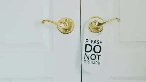 A woman's hand opening a white door slightly and hanging a "please do not d.. Stock Footage 334591495