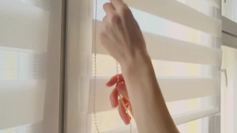 Woman's hand opening white roller blinds on a window. Stock Footage 329768810