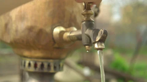 A woman's hand opens the brass tap of the samovar and boiling water flows Stock Footage 153936162