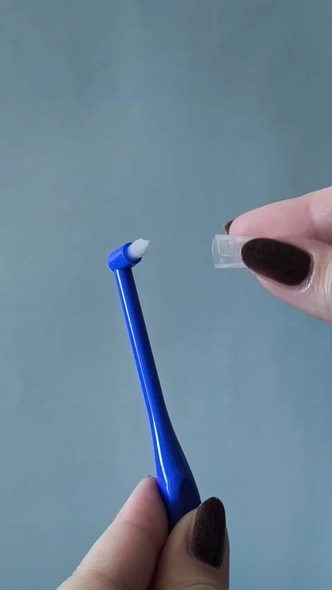 A womans hand opens the cap with a single-tuft toothbrush. Brushing your teeth 库存影片 329969499