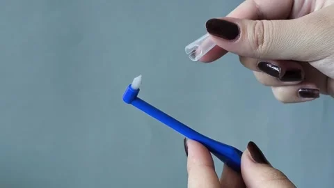 A womans hand opens the cap with a single-tuft toothbrush. Brushing your teeth 库存影片 329969532