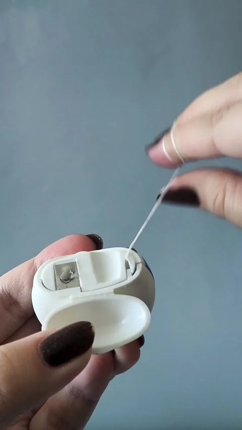 A womans hand opens the container and pulls the dental floss out of the 库存影片 329969578