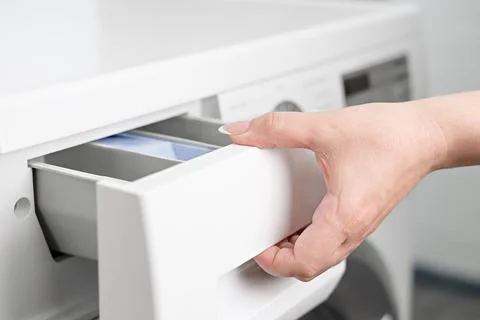 A woman's hand opens the detergent drawer in a washing machine Stock Photos