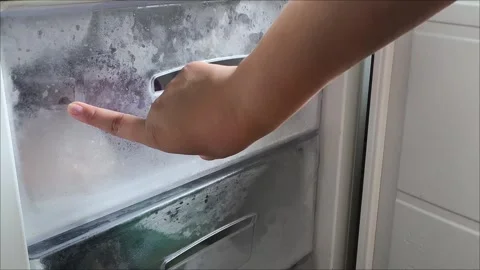A womans hand opens the freezer door in the refrigerator and pulls out a 動画素材 313834269